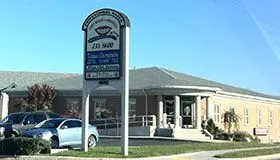 A building with a sign in front of it and cars parked in front of it.